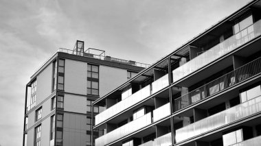 Güneş ışınları kentsel binalar üzerinde ışık etkisi yaratıyor. Düz binaları olan modern bir apartman dairesi. Yeni lüks ev ve kompleksin ayrıntıları. Siyah ve beyaz.