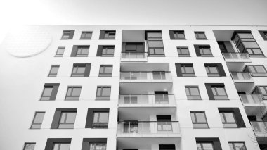 Güneş ışınları kentsel binalar üzerinde ışık etkisi yaratıyor. Düz binaları olan modern bir apartman dairesi. Yeni lüks ev ve kompleksin ayrıntıları. Siyah ve beyaz.