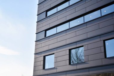 Koyu gri cepheli modern bir binanın düz bir cephesi. Koyu gri metalik panel cephesi. Modern mimari ayrıntılar. 