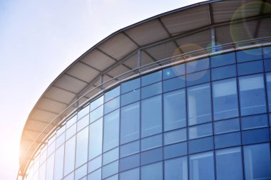 Modern architecture with sun ray. Glass facade on a bright sunny day with sunbeams in the blue sky.