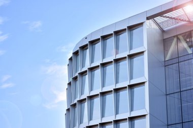 Modern architecture with sun ray. Glass facade on a bright sunny day with sunbeams in the blue sky.