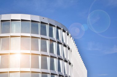 Modern architecture with sun ray. Glass facade on a bright sunny day with sunbeams in the blue sky.