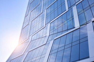 Modern architecture with sun ray. Glass facade on a bright sunny day with sunbeams in the blue sky.