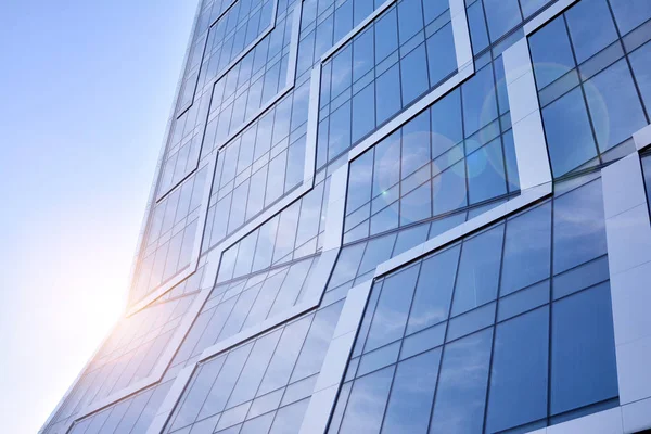 Modern architecture with sun ray. Glass facade on a bright sunny day with sunbeams in the blue sky.
