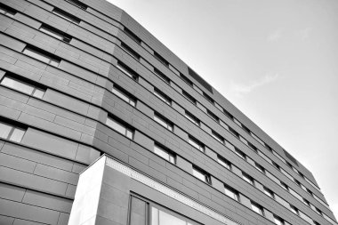 A view at a straight facade of a modern building with a dark grey facade. Dark grey metallic panel facad. Modern architectural details. Black and white.