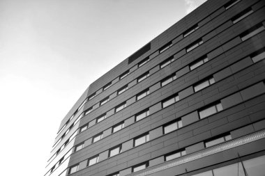 A view at a straight facade of a modern building with a dark grey facade. Dark grey metallic panel facad. Modern architectural details. Black and white.
