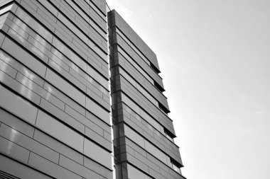 A view at a straight facade of a modern building with a dark grey facade. Dark grey metallic panel facad. Modern architectural details. Black and white.