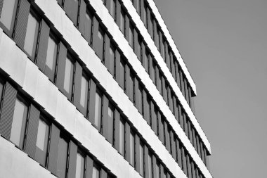 A view at a straight facade of a modern building with a dark grey facade. Dark grey metallic panel facad. Modern architectural details. Black and white.