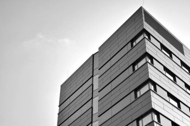 A view at a straight facade of a modern building with a dark grey facade. Dark grey metallic panel facad. Modern architectural details. Black and white.
