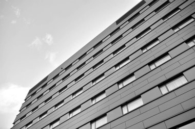 A view at a straight facade of a modern building with a dark grey facade. Dark grey metallic panel facad. Modern architectural details. Black and white.
