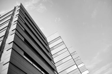 A view at a straight facade of a modern building with a dark grey facade. Dark grey metallic panel facad. Modern architectural details. Black and white.