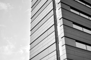 A view at a straight facade of a modern building with a dark grey facade. Dark grey metallic panel facad. Modern architectural details. Black and white.