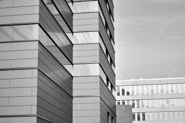 A view at a straight facade of a modern building with a dark grey facade. Dark grey metallic panel facad. Modern architectural details. Black and white.