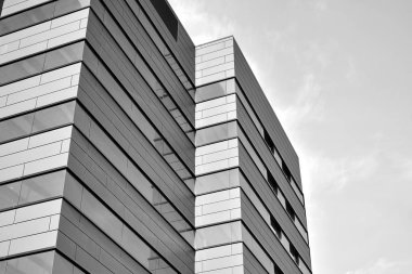 A view at a straight facade of a modern building with a dark grey facade. Dark grey metallic panel facad. Modern architectural details. Black and white.