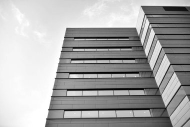A view at a straight facade of a modern building with a dark grey facade. Dark grey metallic panel facad. Modern architectural details. Black and white.