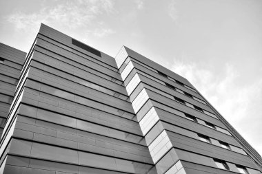 A view at a straight facade of a modern building with a dark grey facade. Dark grey metallic panel facad. Modern architectural details. Black and white.