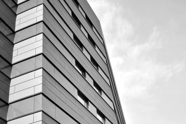 A view at a straight facade of a modern building with a dark grey facade. Dark grey metallic panel facad. Modern architectural details. Black and white.
