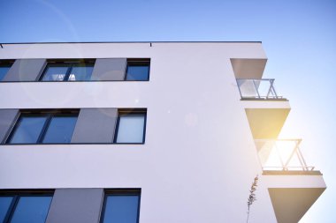 Modern multi story building being lit by the setting sun at afternoon. New apartment house residential building outdoor concept.