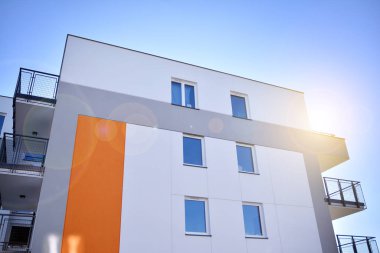 Modern multi story building being lit by the setting sun at afternoon. New apartment house residential building outdoor concept.