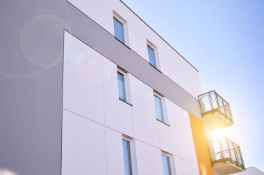 Modern multi story building being lit by the setting sun at afternoon. New apartment house residential building outdoor concept.