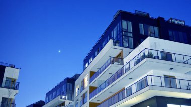 House building and city construction concept: evening outdoor urban view of modern real estate homes. View of balconies of apartment building at night.
