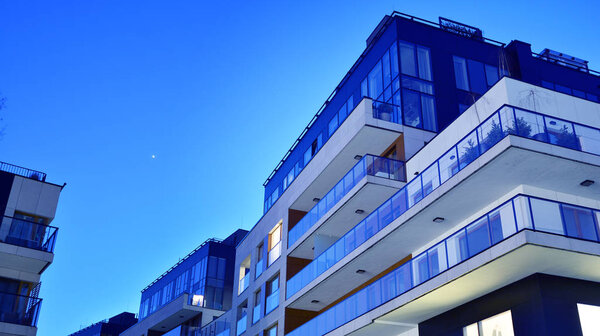 House building and city construction concept: evening outdoor urban view of modern real estate homes. View of balconies of apartment building at night.