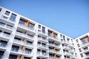Gündüz gözüyle modern yerleşim yerinin dış tarafında. Mavi gökyüzü olan güneşli bir günde modern apartman binaları. Modern bir apartmanın cephesi