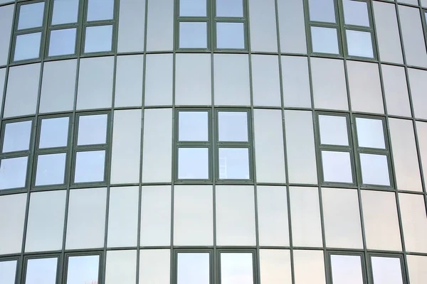 Glass transparent windows on the facade of a modern office or commercial building. Building in the center of a big city reflect the blue sky.