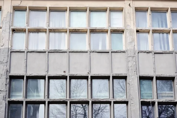 Facade of an old industrial office building with a predominance of old cement and old structural elements.