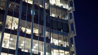 Ofis binalarının pencereleri gece aydınlandı. Şehir merkezinde yansıması olan cam mimari cephe tasarımı ile ışıklandırma.