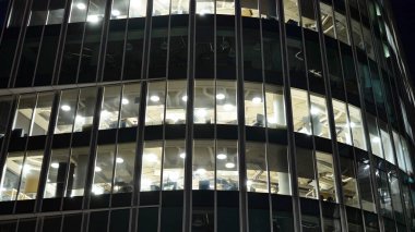 Ofis binalarının pencereleri gece aydınlandı. Şehir merkezinde yansıması olan cam mimari cephe tasarımı ile ışıklandırma.