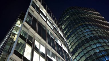 Ofis binalarının pencereleri gece aydınlandı. Şehir merkezinde yansıması olan cam mimari cephe tasarımı ile ışıklandırma.