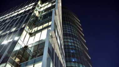 Ofis binalarının pencereleri gece aydınlandı. Şehir merkezinde yansıması olan cam mimari cephe tasarımı ile ışıklandırma.