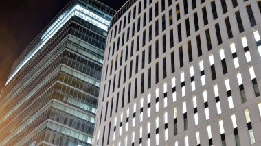 Ofis binalarının pencereleri gece aydınlandı. Şehir merkezinde yansıması olan cam mimari cephe tasarımı ile ışıklandırma.