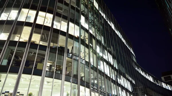 Pattern of office buildings windows illuminated at night. Lighting with Glass architecture facade design with reflection in urban city.
