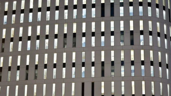 Pattern of office buildings windows illuminated at night. Lighting with Glass architecture facade design with reflection in urban city.