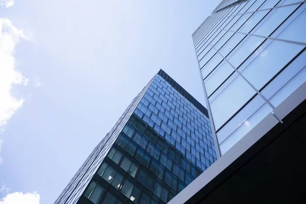 Modern curtain wall made of glass and steel. Blue sky and clouds reflected in windows of modern office building.