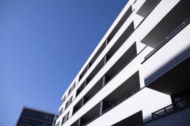 Mavi gökyüzü olan güneşli bir günde modern apartman binaları. Modern bir apartmanın cephesi