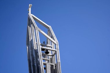 Mavi gökyüzünün altındaki modern kilisenin çan kulesinde çapraz. 