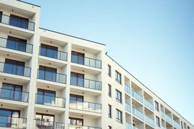 Mavi gökyüzü olan güneşli bir günde modern apartman binaları. Modern bir apartmanın cephesi