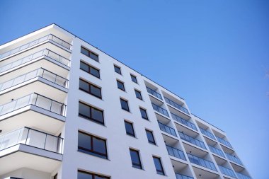 Mavi gökyüzü olan güneşli bir günde modern apartman binaları. Modern bir apartmanın cephesi