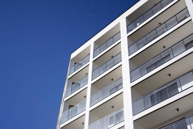 Mavi gökyüzü olan güneşli bir günde modern apartman binaları. Modern bir apartmanın cephesi