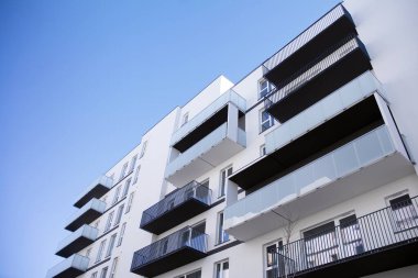 Mavi gökyüzü olan güneşli bir günde modern apartman binaları. Modern bir apartmanın cephesi