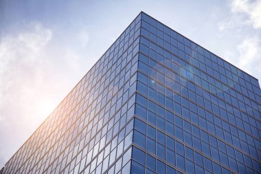 Açık güneşli bir günde mavi gökyüzünde güneş ışınlarıyla cam cepheler inşa eden ofis. Güneş ışığına sahip bir gökdelenin soyut görüntüsü