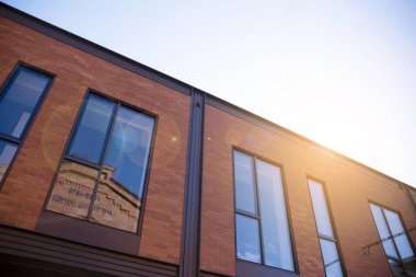 Açık güneşli bir günde mavi gökyüzünde güneş ışınlarıyla cam cepheler inşa eden ofis. Güneş ışığına sahip bir gökdelenin soyut görüntüsü