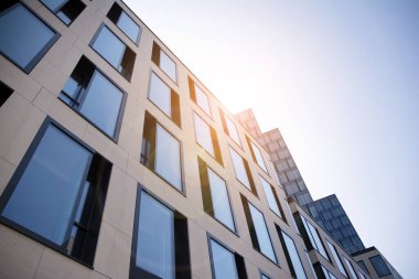 Gökdelen, şehirde günışığı olan modern bir bina. Gün ışığında bir ofis binasının cam duvarı. Ofis penceresi gün doğumu, yansıma ve perspektifle kapanıyor.