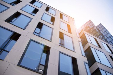 Gökdelen, şehirde günışığı olan modern bir bina. Gün ışığında bir ofis binasının cam duvarı. Ofis penceresi gün doğumu, yansıma ve perspektifle kapanıyor.