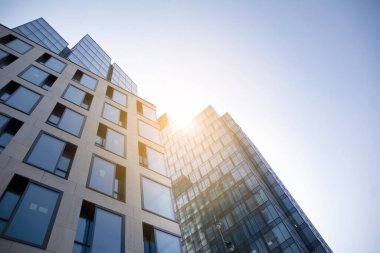 Gökdelen, şehirde günışığı olan modern bir bina. Gün ışığında bir ofis binasının cam duvarı. Ofis penceresi gün doğumu, yansıma ve perspektifle kapanıyor.