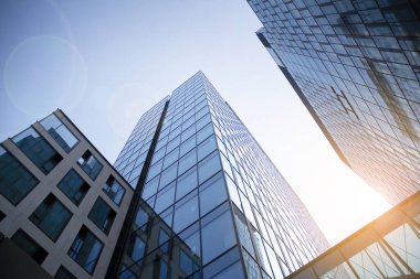 Gökdelen, şehirde günışığı olan modern bir bina. Gün ışığında bir ofis binasının cam duvarı. Ofis penceresi gün doğumu, yansıma ve perspektifle kapanıyor.