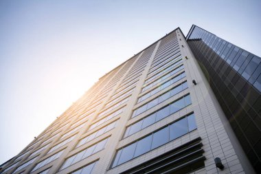 Gökdelen, şehirde günışığı olan modern bir bina. Gün ışığında bir ofis binasının cam duvarı. Ofis penceresi gün doğumu, yansıma ve perspektifle kapanıyor.